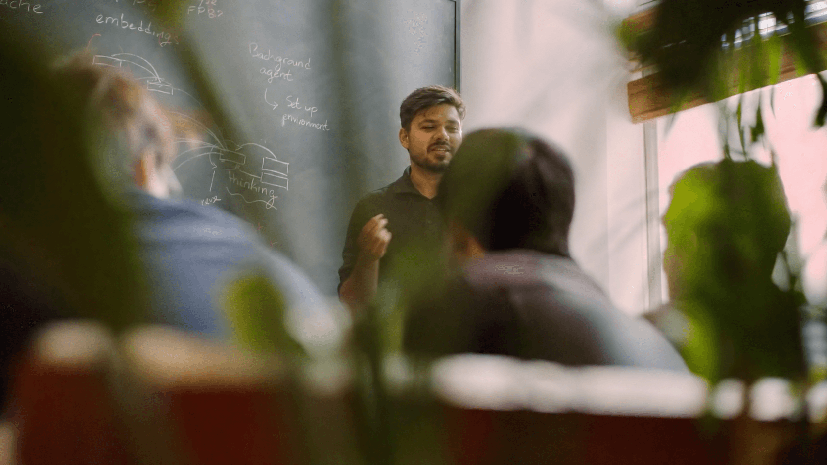 A working session at the chalkboard, seen past the team